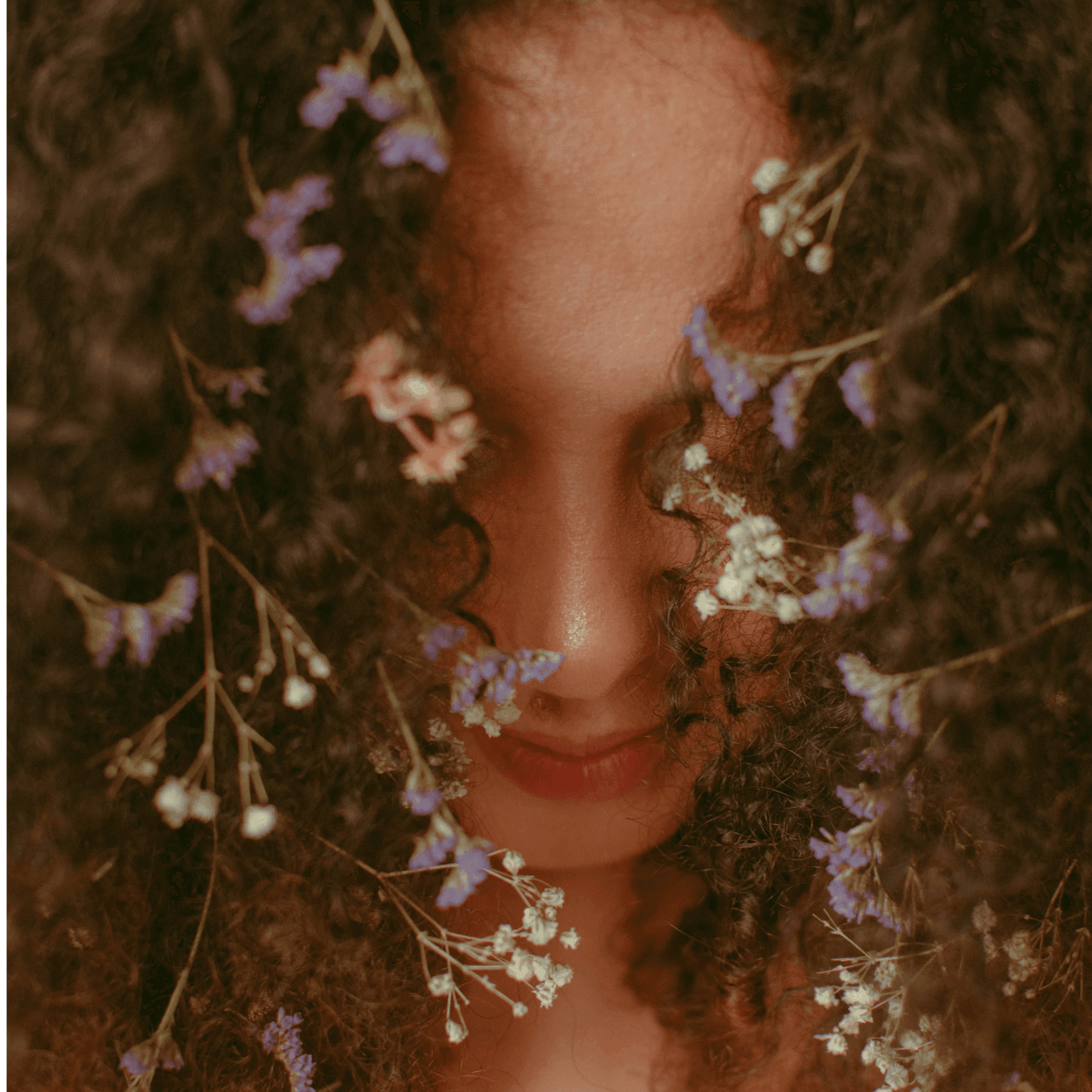 Woman with curly hair and flowers in her hair, symbolizing natural care with Sphagnum Botanicals scalp shampoo for curly and sensitive hair.