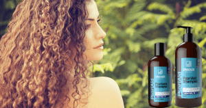 Curly-haired woman looking over her shoulder at two Sphagnum Botanicals psoriasis shampoo bottles with a forest background.