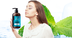Woman with eyes closed smelling a Sphagnum Botanicals Psoriasis Shampoo bottle in her hand, mint leaves background