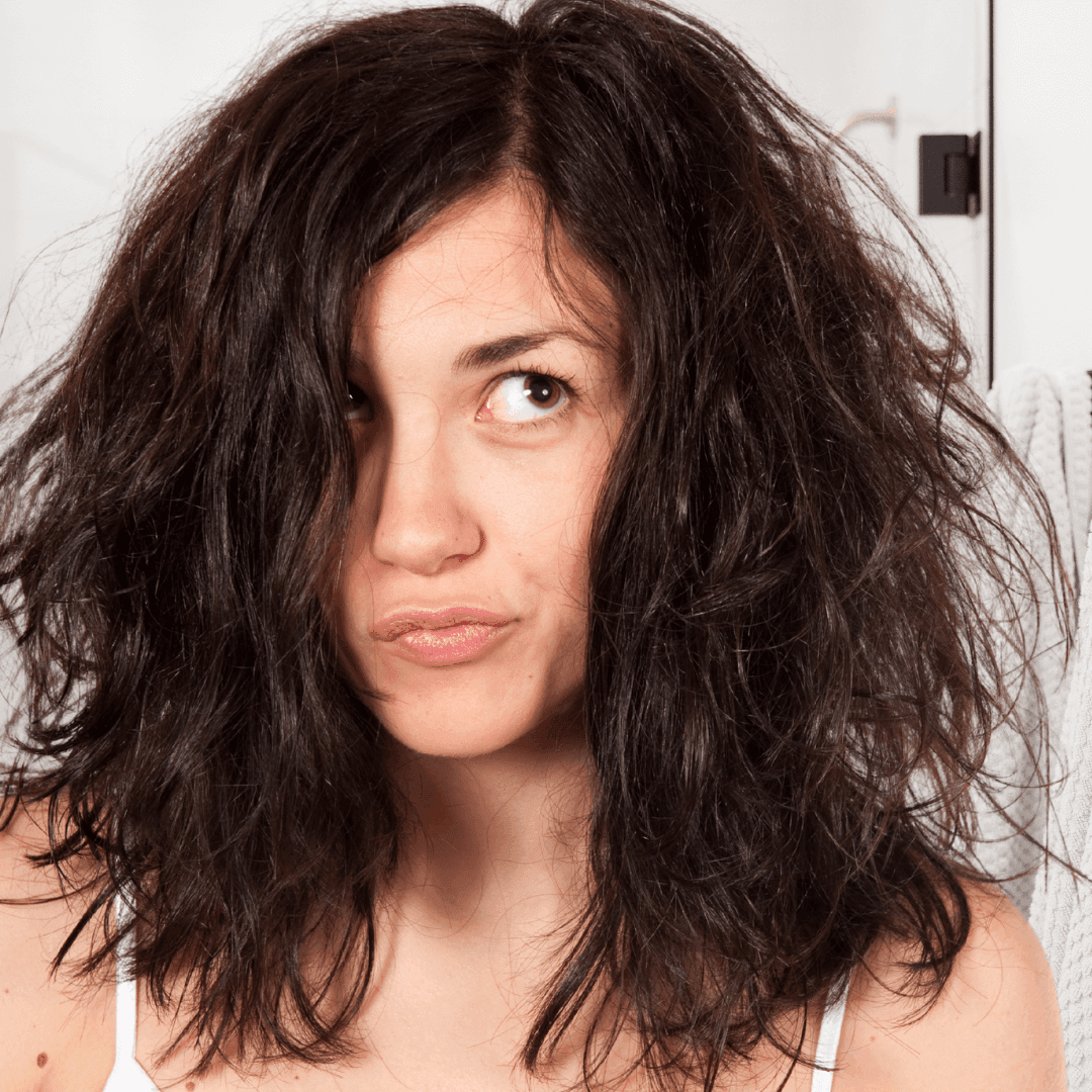 Woman with shoulder-length brown hair thinking about her hair routine beside a Sphagnum Botanicals Psoriasis Shampoo bottle