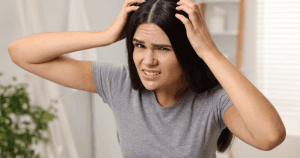 Woman touching itchy scalp with dandruff, showing relief from Sphagnum Botanicals itchy scalp shampoo with salicylic acid.