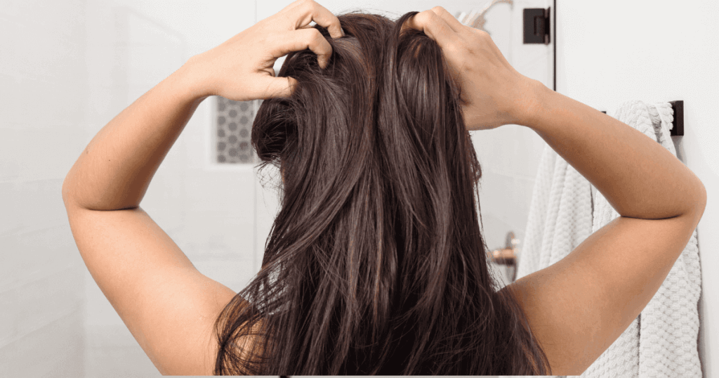 Back view: brunette holding scalp due to itch and dryness