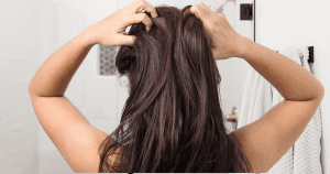 Back view: brunette holding scalp due to itch and dryness